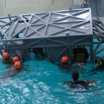 Alunos utilizando equipamento que simula a queda de aeronave em ambiente aquático
