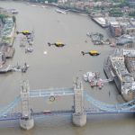 Três helicopteros EC145s da Unidade Policial Metropolitana de Apoio Aéreo a voando sobre a ponte da torre de Londres enfeitada com os anéis Olímpicos