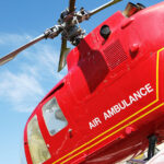 Red helicopter of air ambulance isolated on blue sky background.